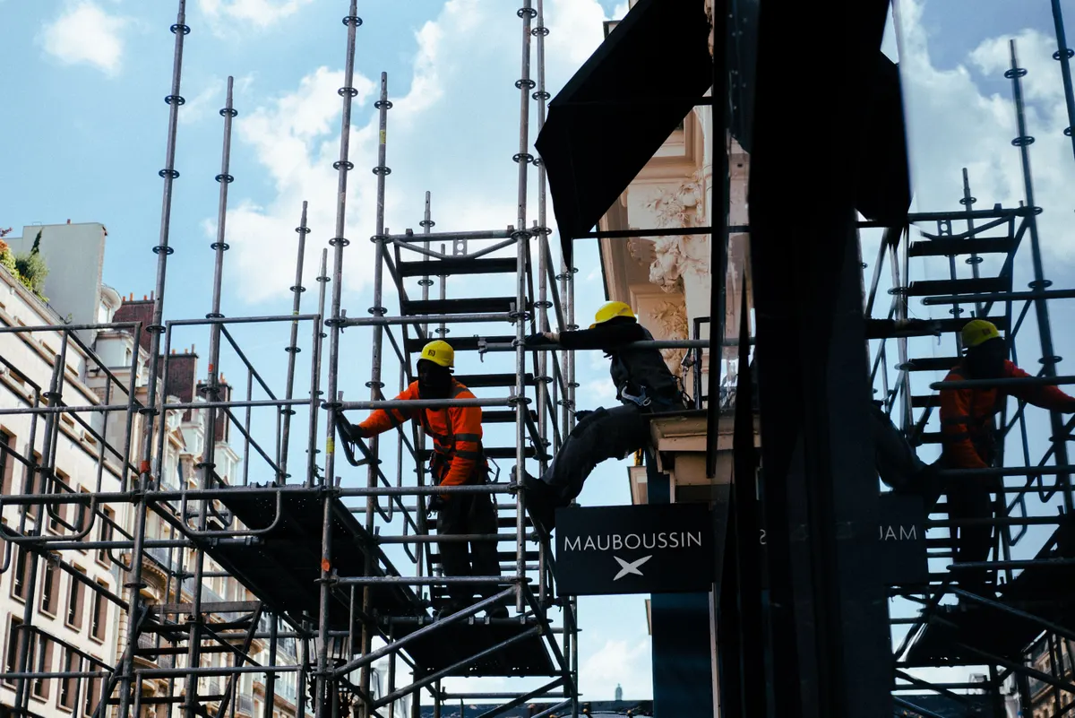 Operários montando andaimes metálicos contra o céu azul