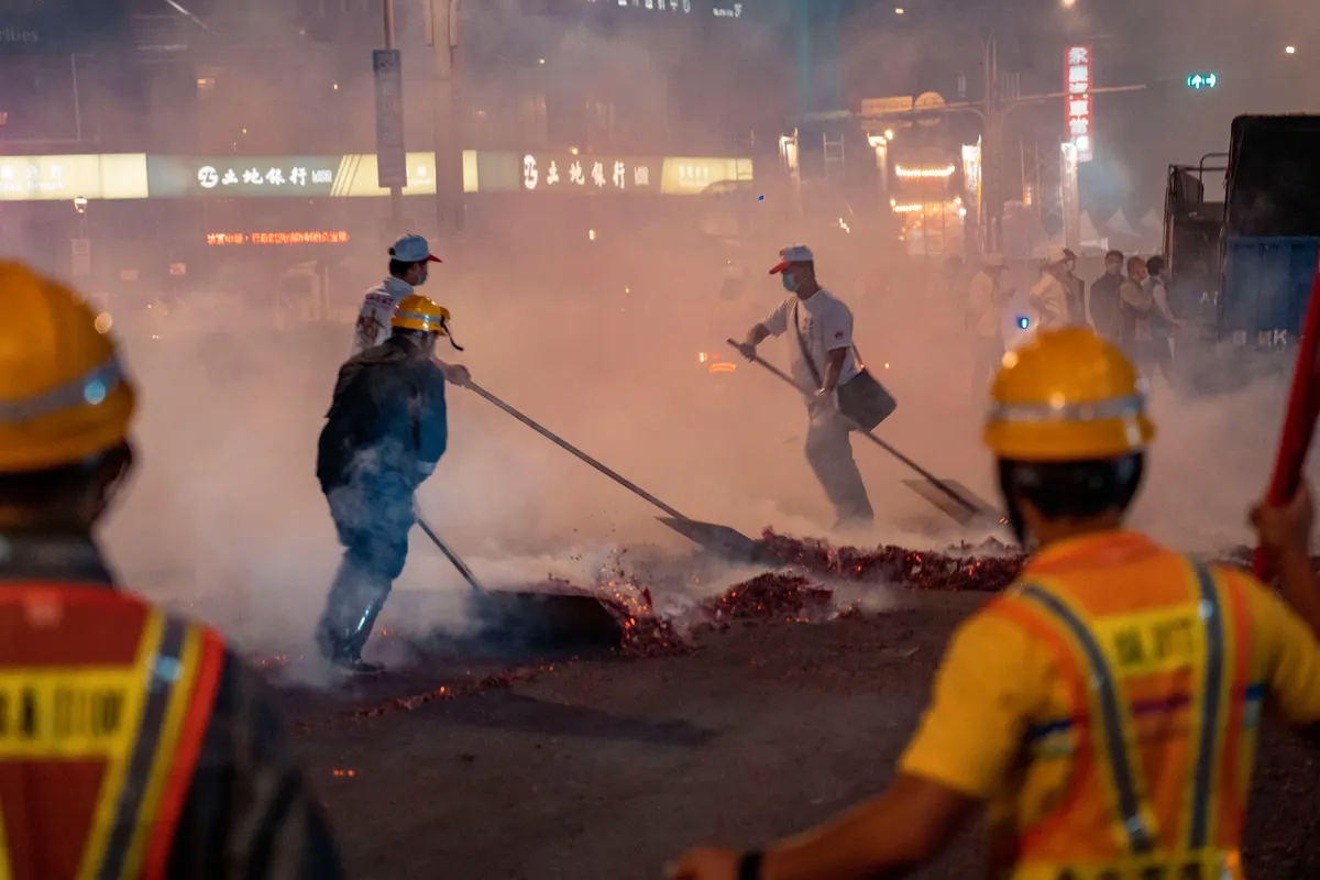 Equipe de uniforme e capacete trabalhando à noite em meio a fumaça densa