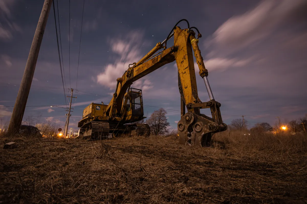 Escavadeira sobre terreno aberto recortada contra o céu no crepúsculo