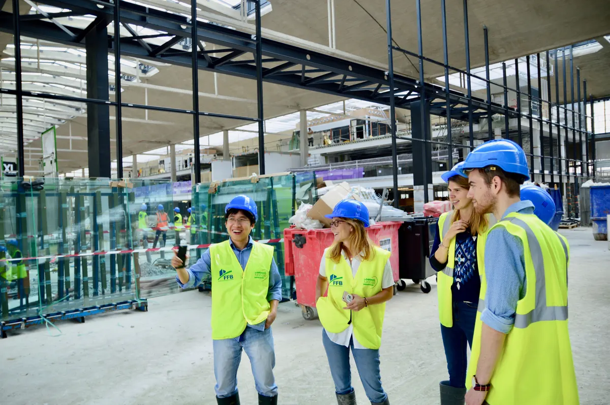 Grupo de profissionais de colete e capacete reunidos em obra industrial
