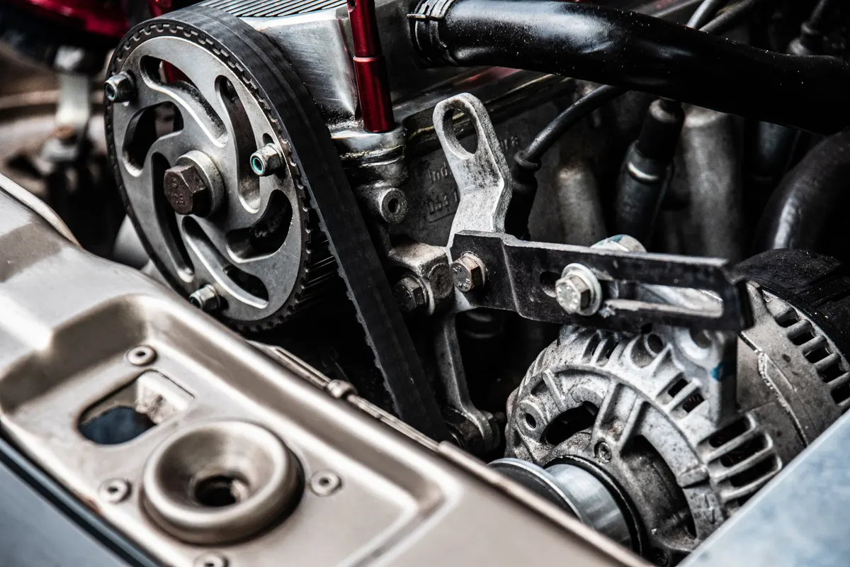 Vista superior de motor com correias, polias e alternador durante manutenção