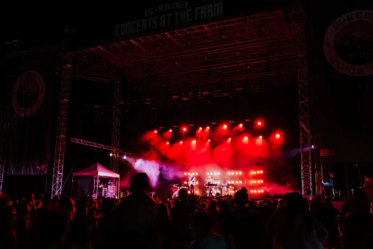 Palco coberto iluminado em luz vermelha durante evento noturno ao ar livre