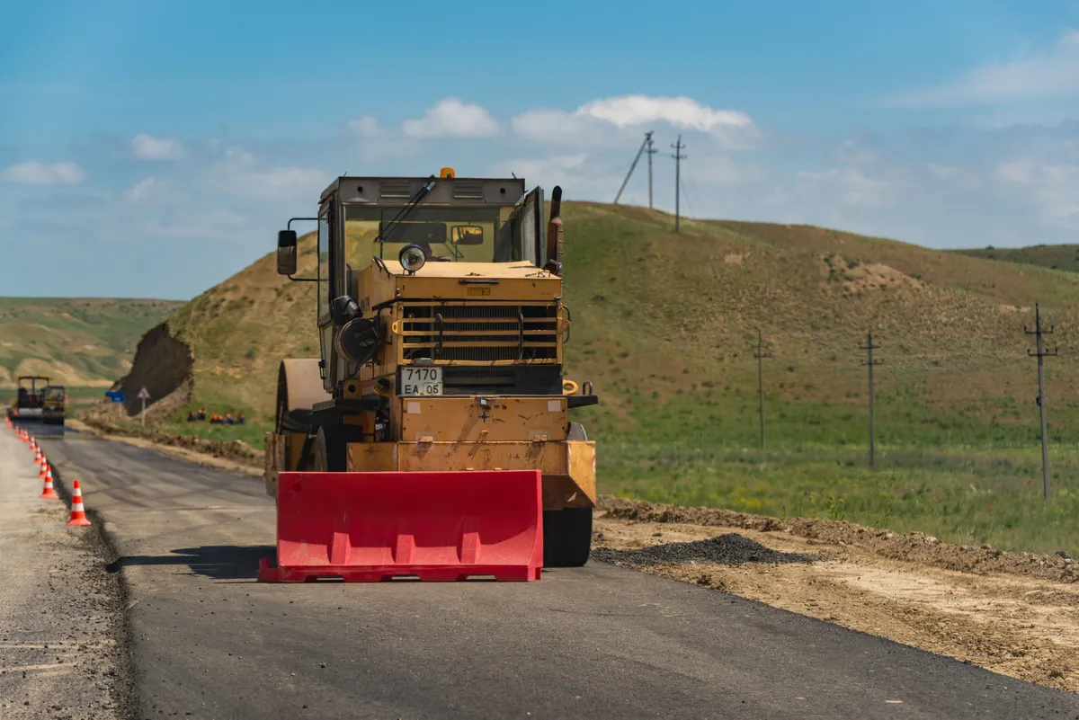 Pavimentadora aplicando asfalto em rodovia de pista simples em área rural
