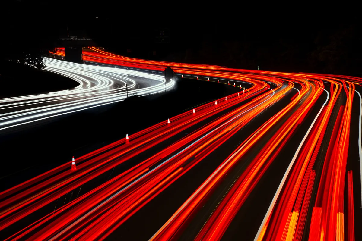 Rastros de luz de veículos em rodovia curvada durante a noite