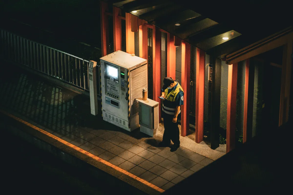 Técnico diante de painel elétrico aberto em galeria iluminada durante a noite