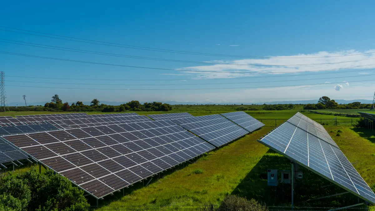 Fileiras de painéis solares instaladas em campo aberto sob céu azul