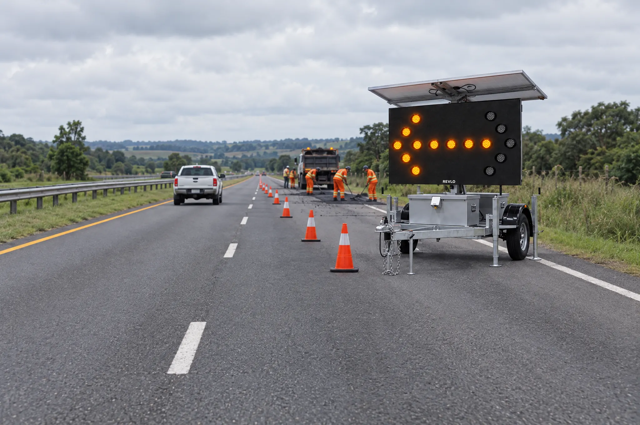 Painel de seta indicativa móvel Revlo numa rodovia de pista dupla, na faixa da direita interditada para reparo do asfalto, com a seta para a esquerda acesa e a cunha de cones levando o trânsito para a faixa da esquerda